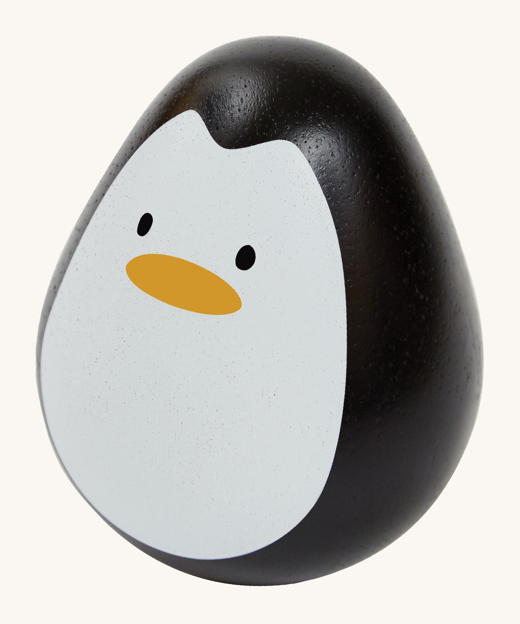 This PlanToys Penguin is a sweet wooden tumbling toy that wobbles and spins. Its size is perfect for little hands, and its smooth texture is perfect for gripping. This wobbling penguin toy is black, with a white face, black eyes and orange beak. The image is on a cream background