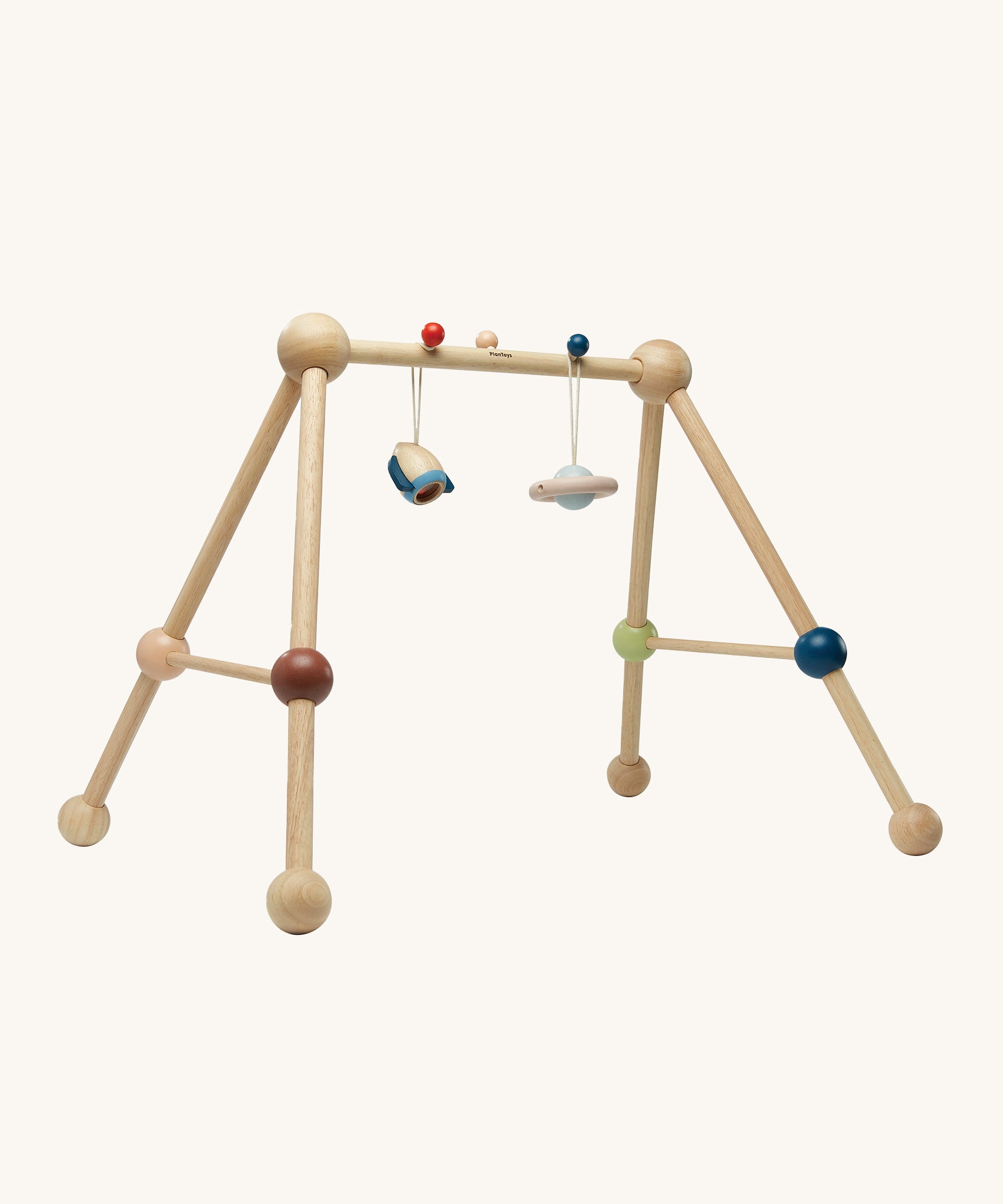 The PlanToys Play Gym Orchard is a fun, sensory baby gym made from wood. This set includes a rocket and a planet toy attached to the top of the baby gym using a red and a blue peg. This is a side view image on a cream background.