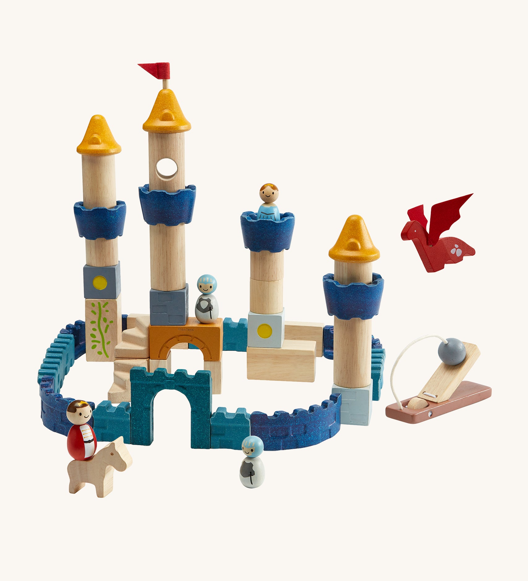 The PlanToys Castle Building Blocks in Orchard colours, made into a colourful castle display. The set comes with castle wall blocks in shades of blue, blocks to make castle towers and turrets, little people figures, a horse, a dragon and a catapult to defend the castle. The image is on a cream background