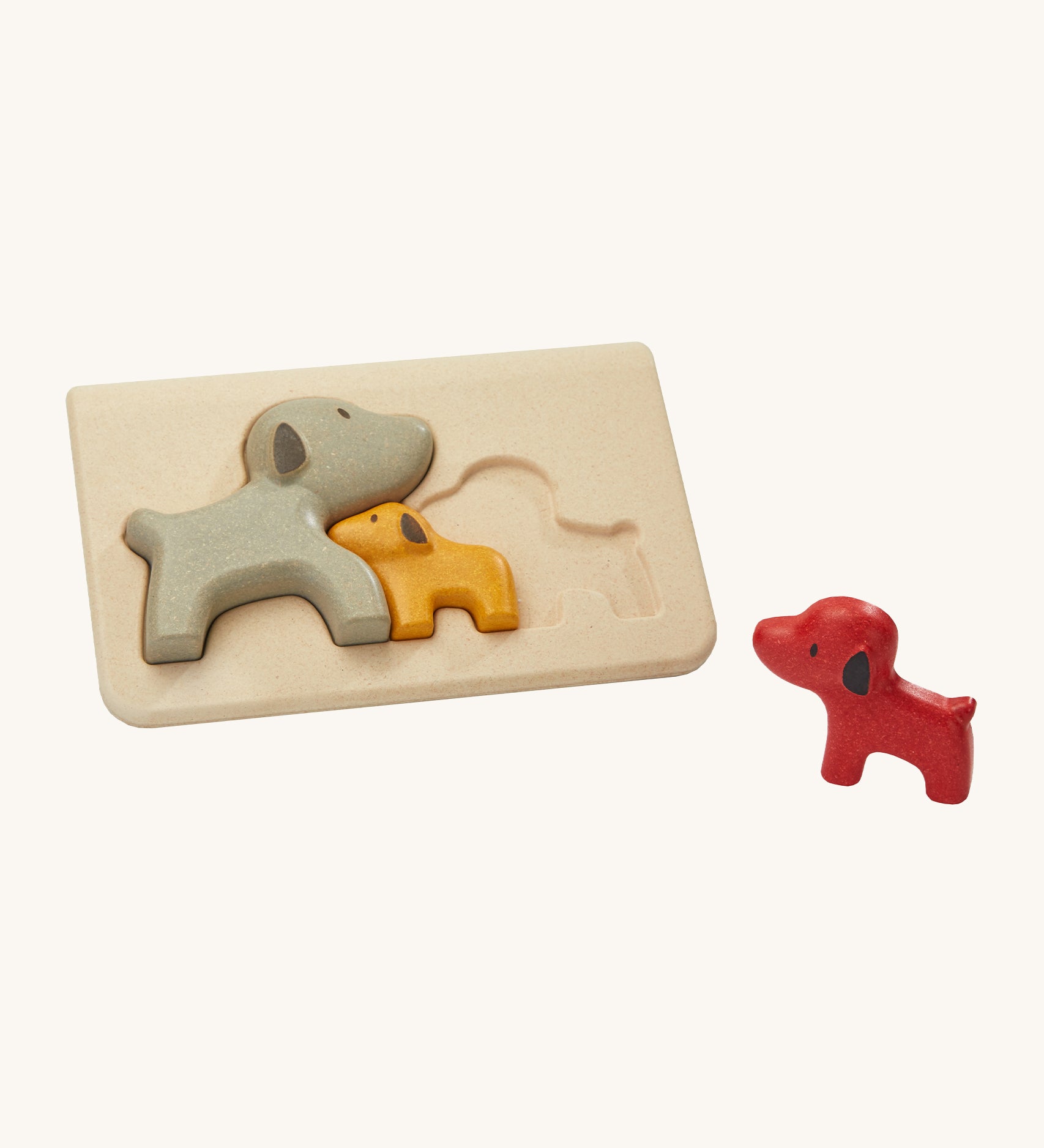 The PlanToys Dog Puzzle, is a fun puzzle toy for little ones. Made from PlanWood, the set comes with a red dog, a yellow dog and a grey dog that when put in the puzzle board, look like they are nesting together. The image is on a cream background