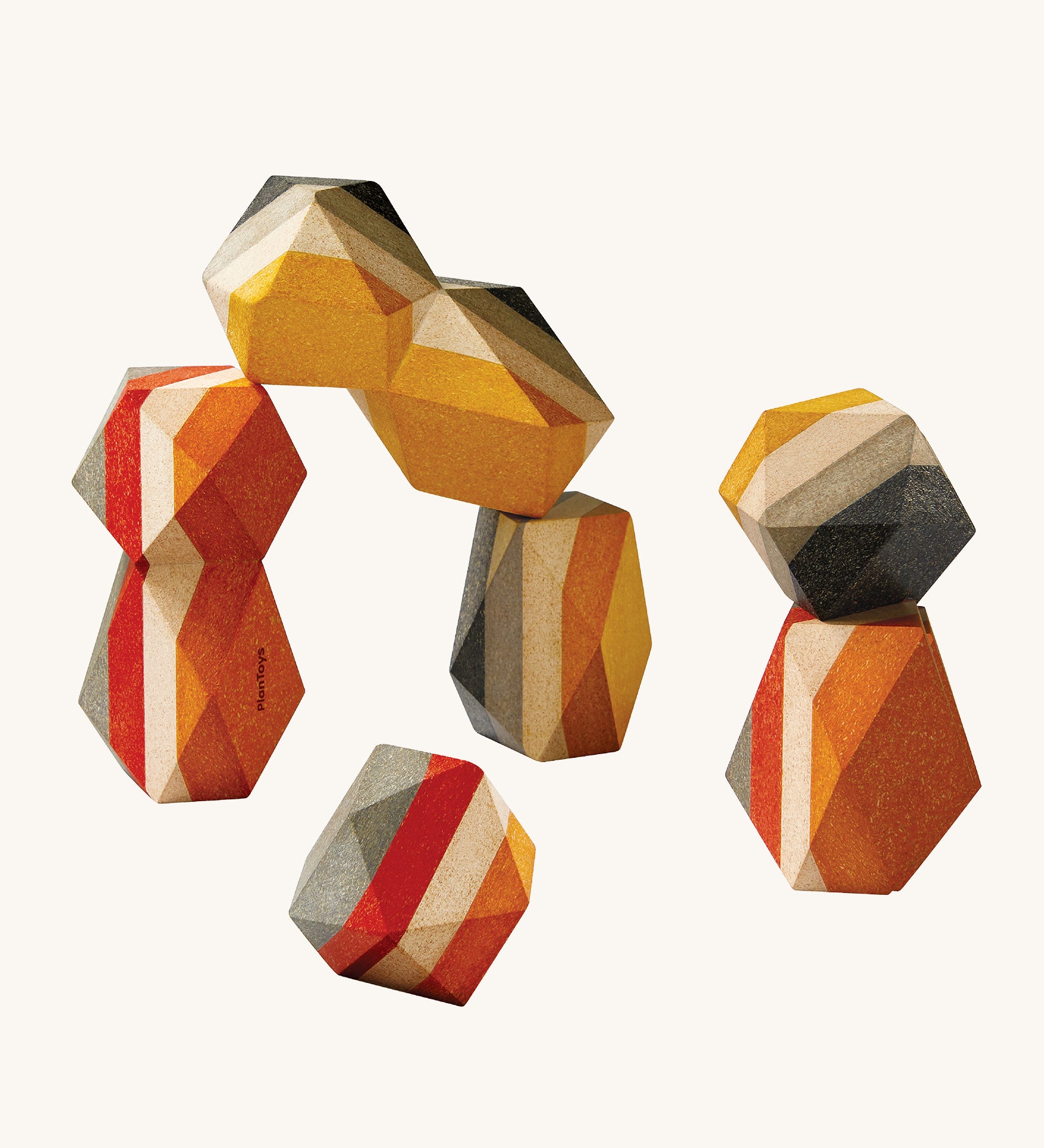 PlanToys Geo Stacking Rocks, are a colourful set of wood blocks with geometric rock shapes. The rocks are striped and are mustard, cream, red and grey in colour. The image is on a cream background