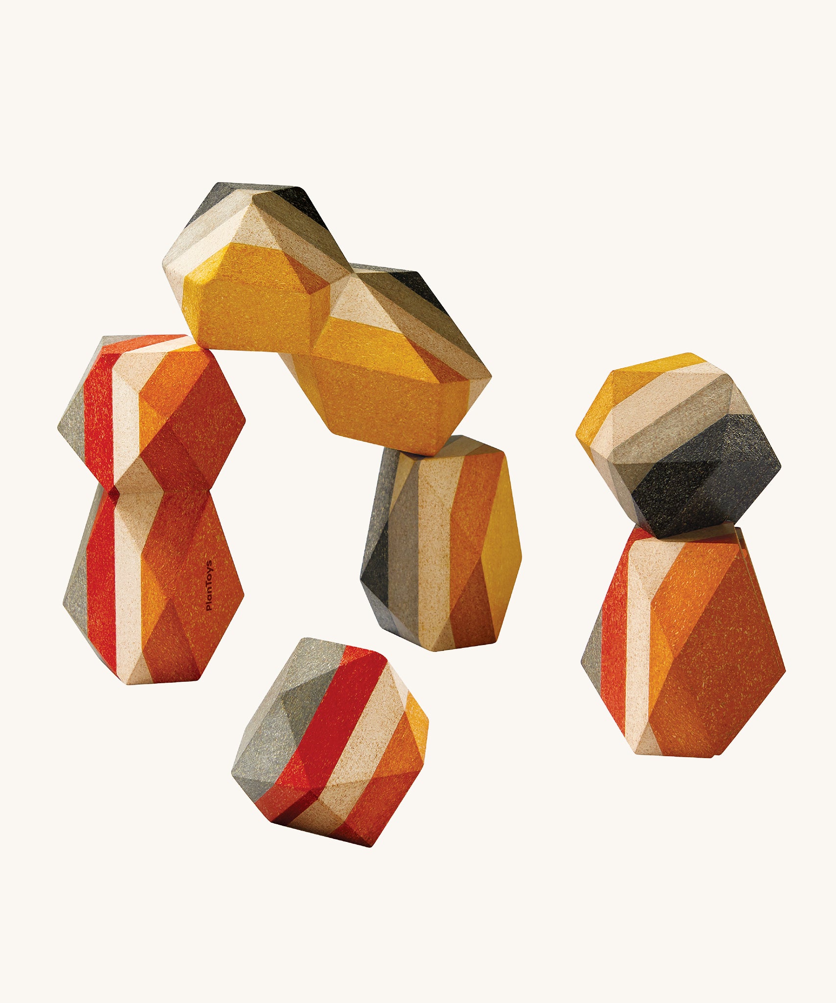 PlanToys Geo Stacking Rocks, are a colourful set of wood blocks with geometric rock shapes. The rocks are striped and are mustard, cream, red and grey in colour. The image is on a cream background