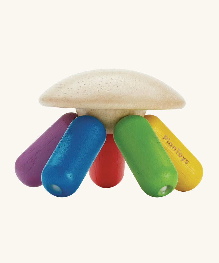 PlanToys plastic-free wooden flexi jellyfish shaped baby sensory and rattle toy in rainbow colours of, green, yellow, red, purple and blue, on a cream background