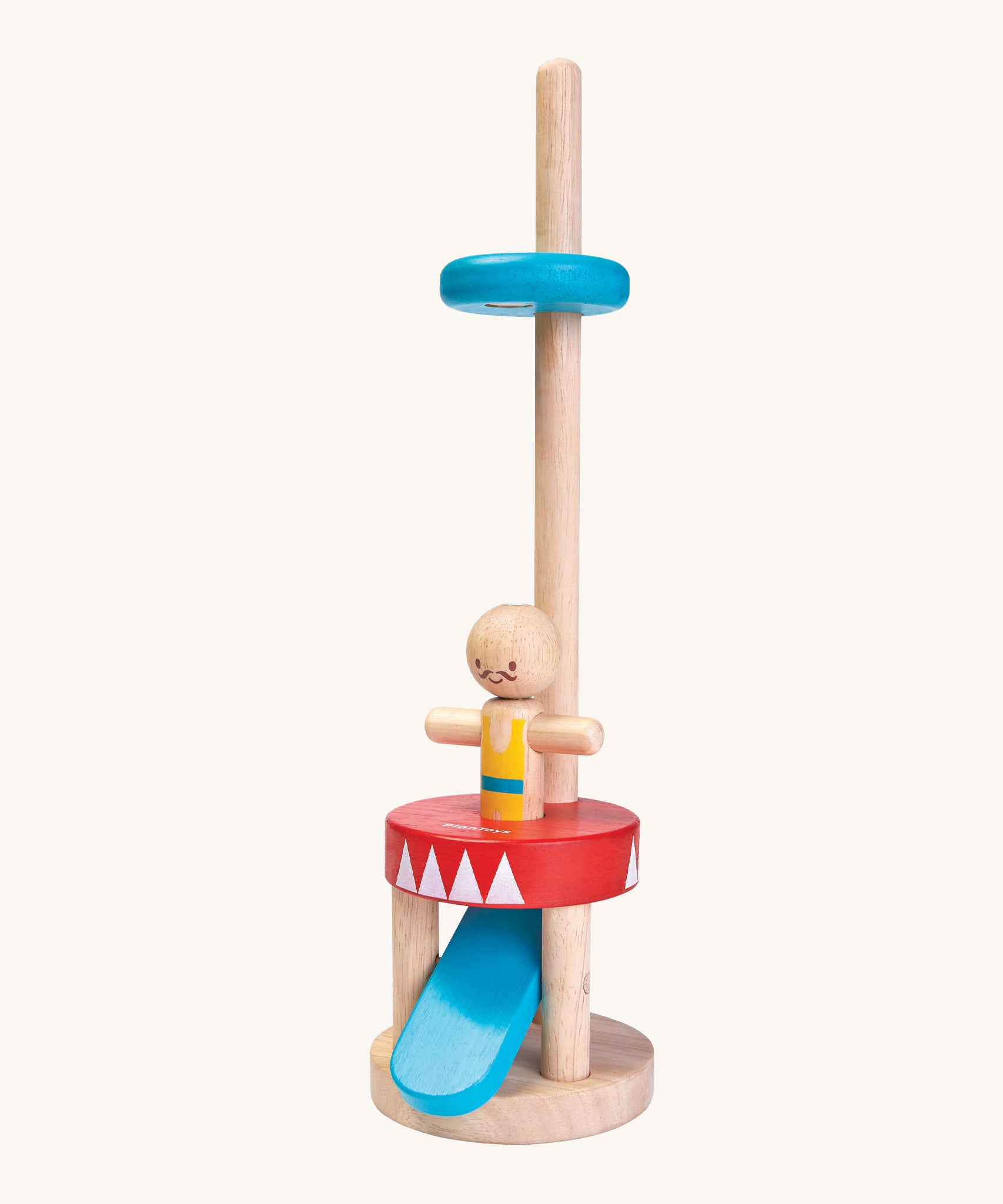 The PlanToys Jumping Acrobat is a magical toy which consists of a wooden peg acrobat with a yellow and blue top, a smiling face with a mustache, a red and white base, a blue push pedal underneath the base, and a blue disk on a wooden pole to catch the figure when it pops up. The image is on a cream background