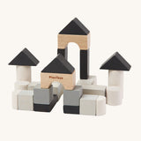 The PlanToys Mini Construction Set with various shaped blocks in shades of grey, black and natural colours on a cream background