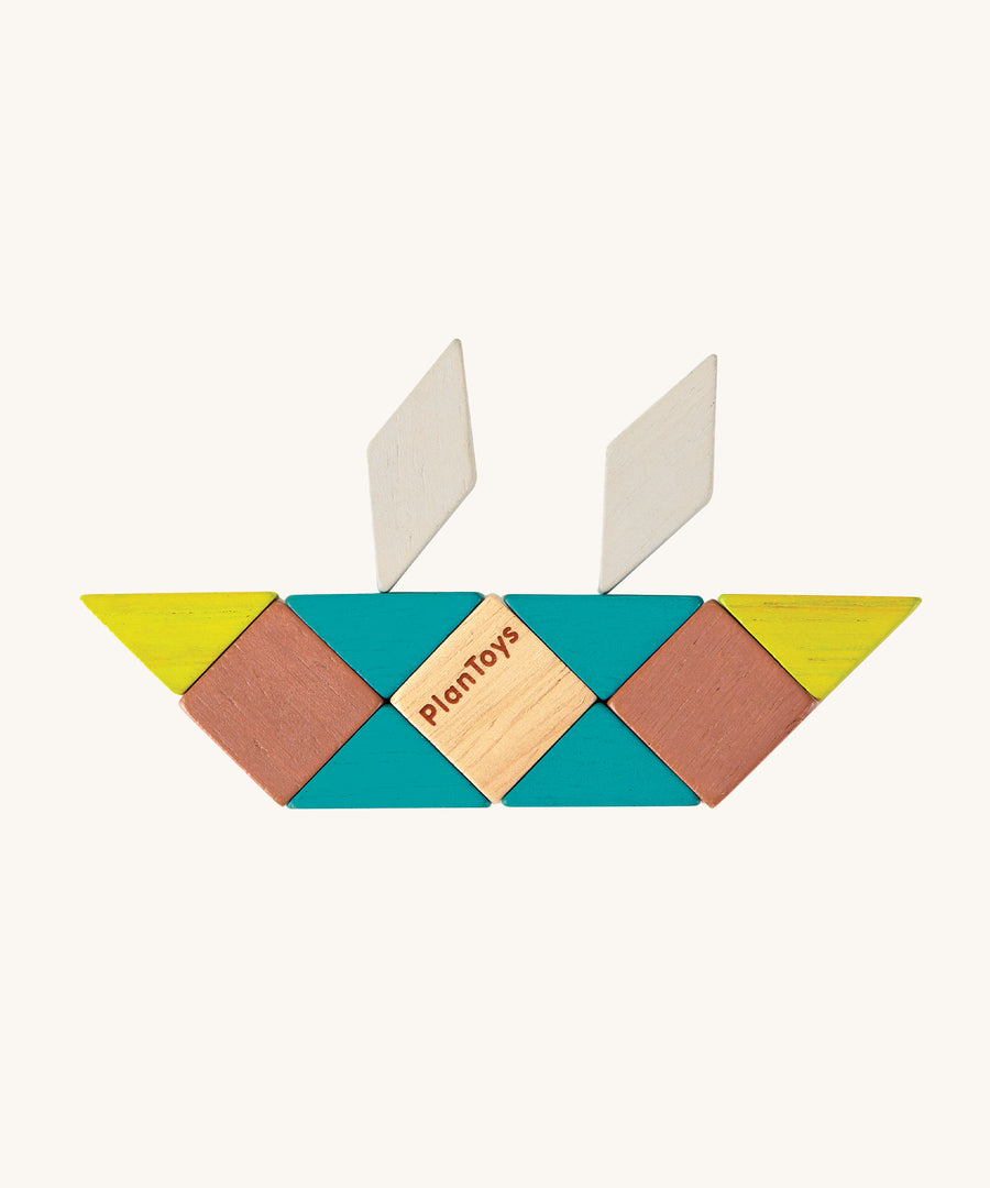 A boat made from the shapes of the PlanToys Mini Mosaic Blocks, on a cream background