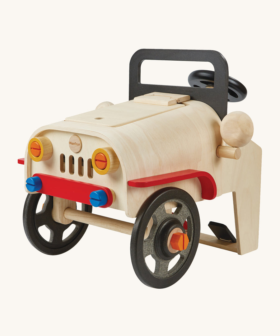 The PlanToys Motor Mechanic, educational toy features lots of removable parts and a wooden engine under the bonnet. The image is on a cream background