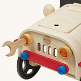 The wooden wrench being used to loosen and tighten the headlights on the PlanToys Motor Mechanic. There are other parts that can also be removed on the front of the car