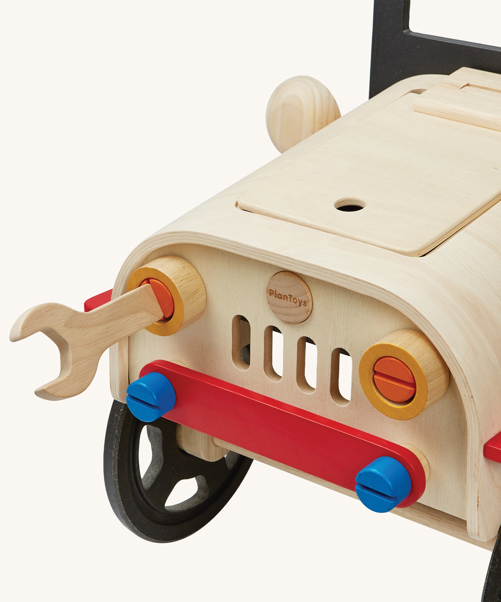 The wooden wrench being used to loosen and tighten the headlights on the PlanToys Motor Mechanic. There are other parts that can also be removed on the front of the car