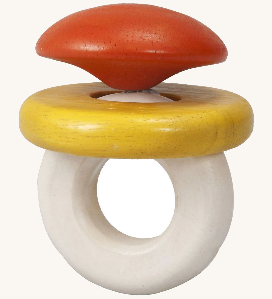 This PlanToys Baby Rattle, is in the shape of a ring, with an orange/red diamond jewel shape on top, a white ring attached for easy grasping, and a horizontal yellow ring which moves. The image is on a cream background