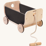 PlanToys Wooden Black Cart Toy, is a lovely push and pull toy with a curved front and back, and black sides. The wagon also come with a removable beige rope and handle, on a cream background