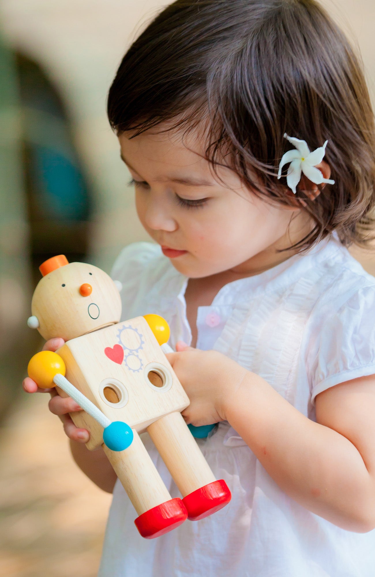 Child holding wooden PlanToys robot and looking at it