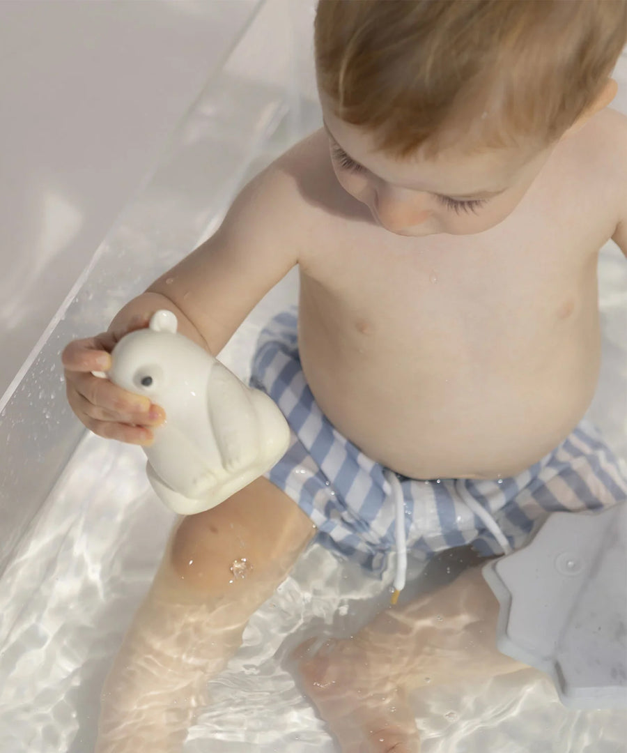 A child playing with the Oli & Carol Polar Bear Bath Toy Set in a bath