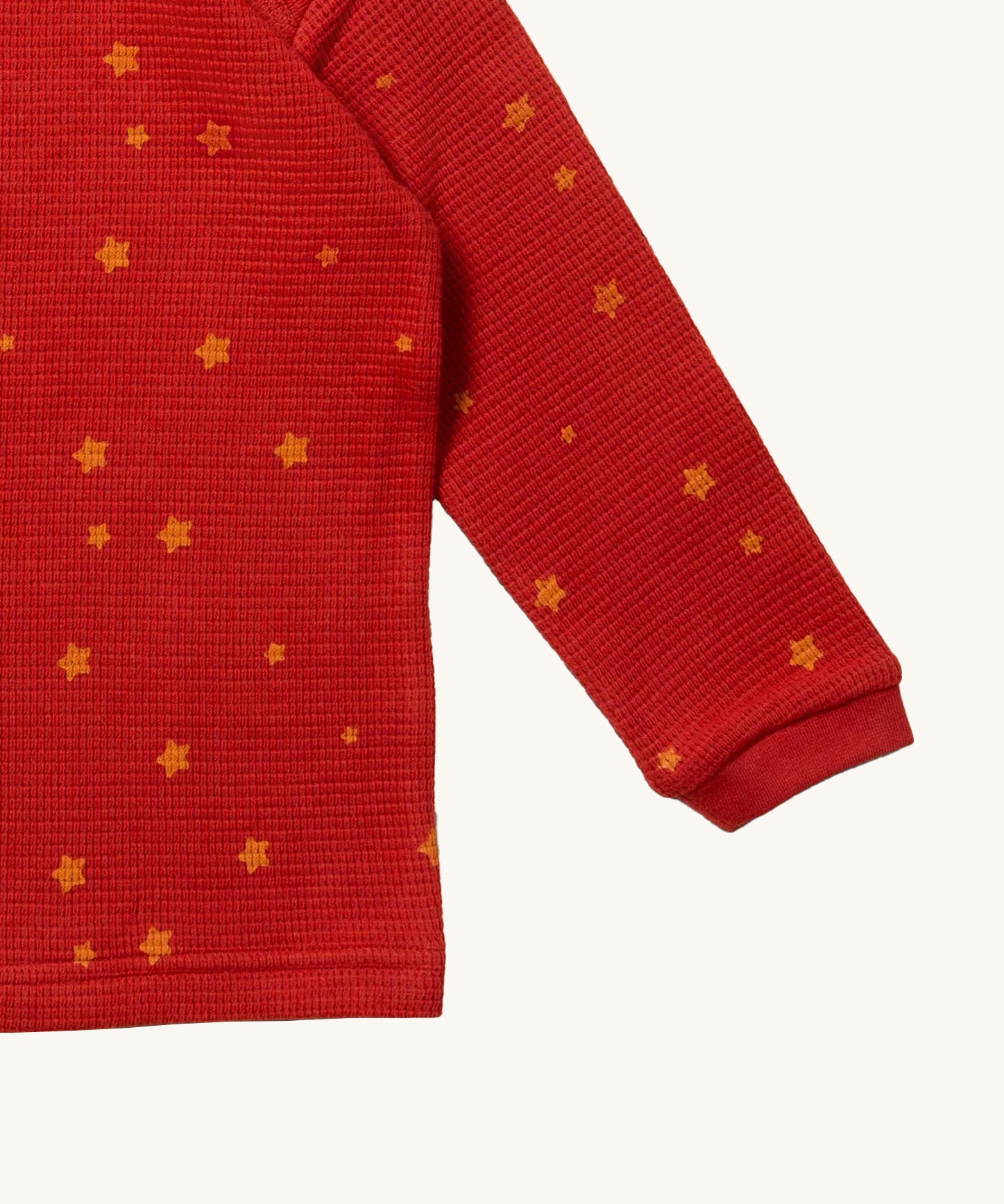 A closer look at the top of the Little Green Radicals Waffle T-Shirt & Jogger Playset - Hazelnut Stars, in red waffle texture fabric and delicate golden stars print