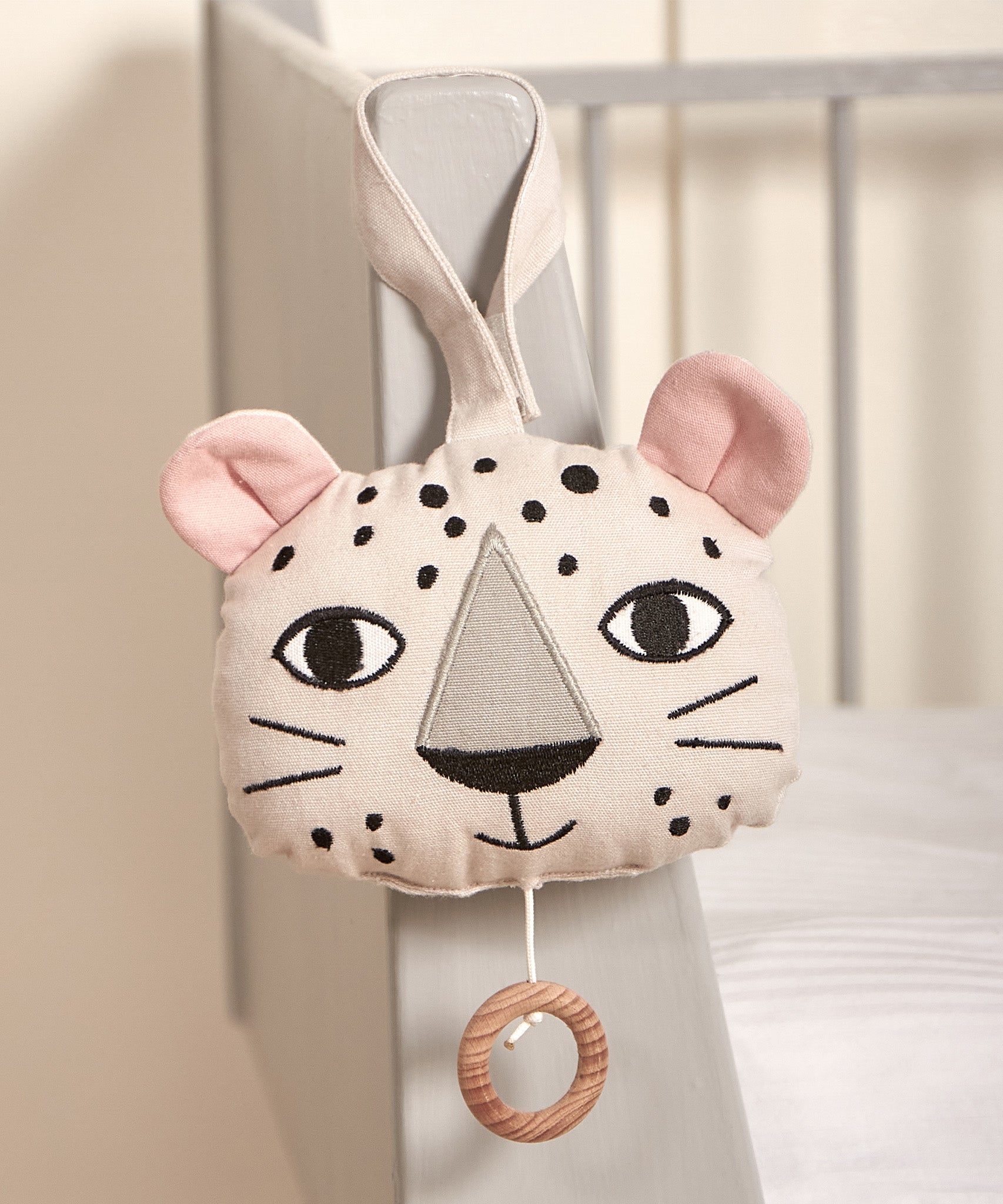 The Roommate Musical Baby Mobile - Leopard hung on the corner of a baby cot bed