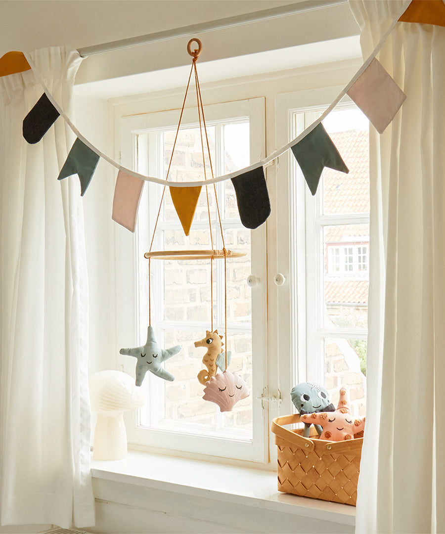 The Roommate Sealife Hanging Mobile hung in front of a window with Roommate Bunting above