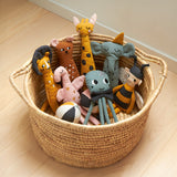 A basket of Roommate Rag Doll Organic Cotton kids toys, stood on a wooden floor