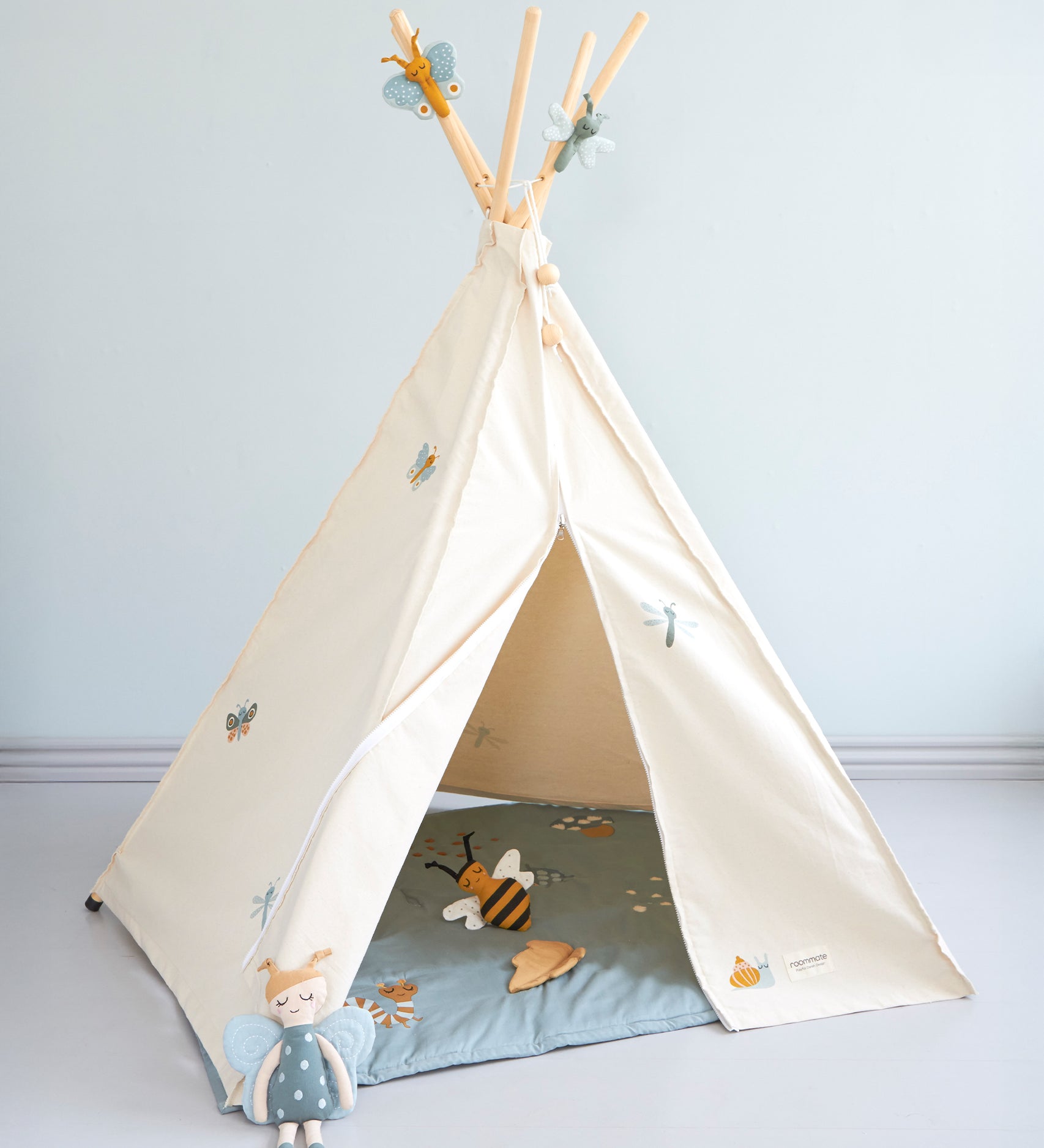 The Roommate Organic Cotton Bee Rattle Toy is laying inside a white Roommate tent with various Roommate toys, on a blue background