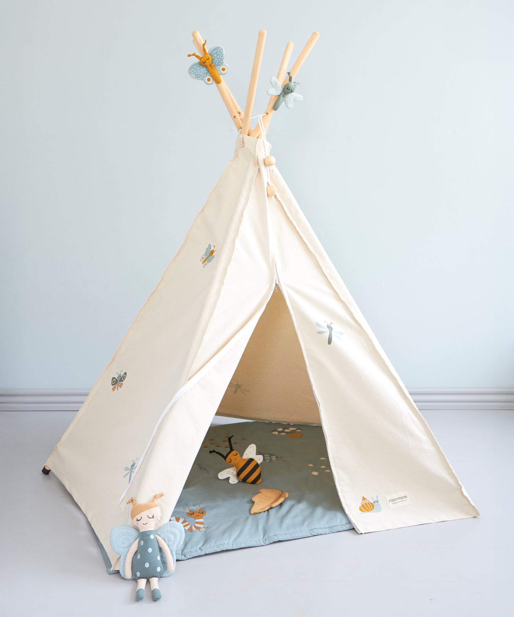 The Roommate Organic Cotton Bee Rattle Toy is laying inside a white Roommate tent with various Roommate toys, on a blue background