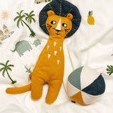 The Roommate Lion Rag Doll toy, laid on a white Roommate bed cover with a Roommate Canvas Ball Toy