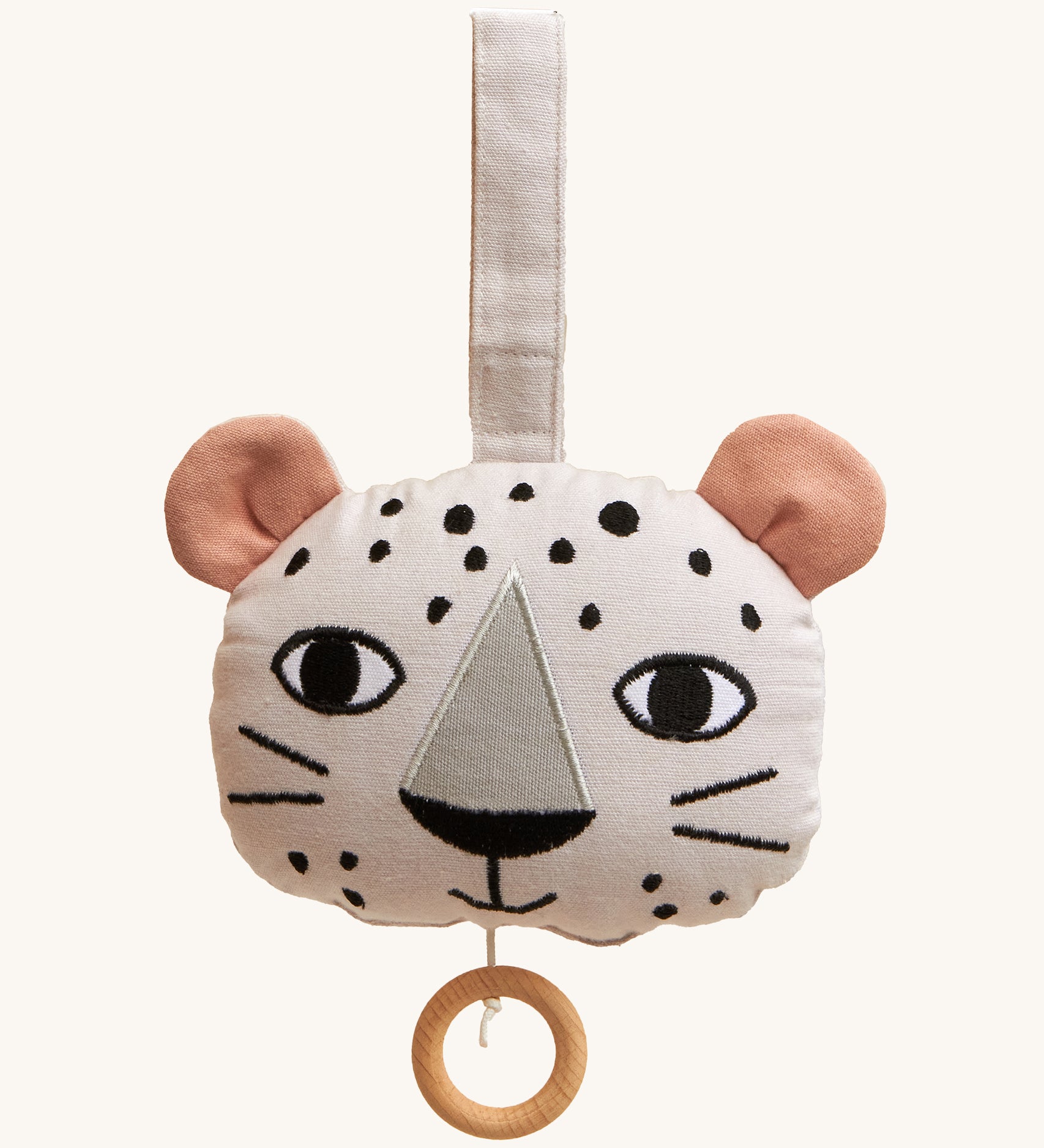 Roommate Musical Baby Mobile - Leopard, in the shape of a leopard face. Made from white fabric with black spots, two pink ears and a pull cord with a wooden hoop handle. On a cream background