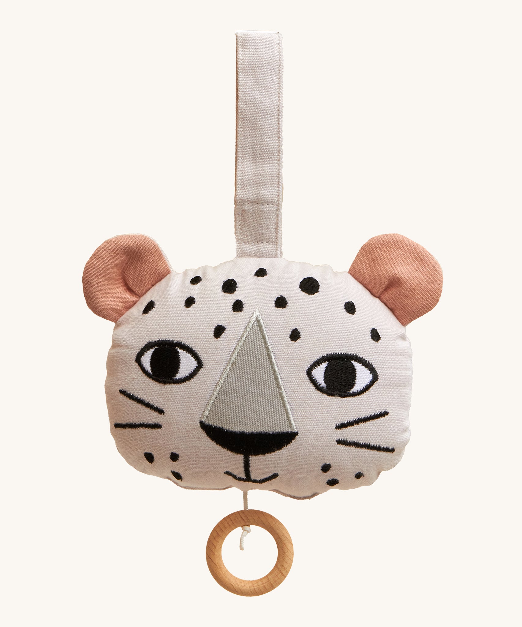 Roommate Musical Baby Mobile - Leopard, in the shape of a leopard face. Made from white fabric with black spots, two pink ears and a pull cord with a wooden hoop handle. On a cream background