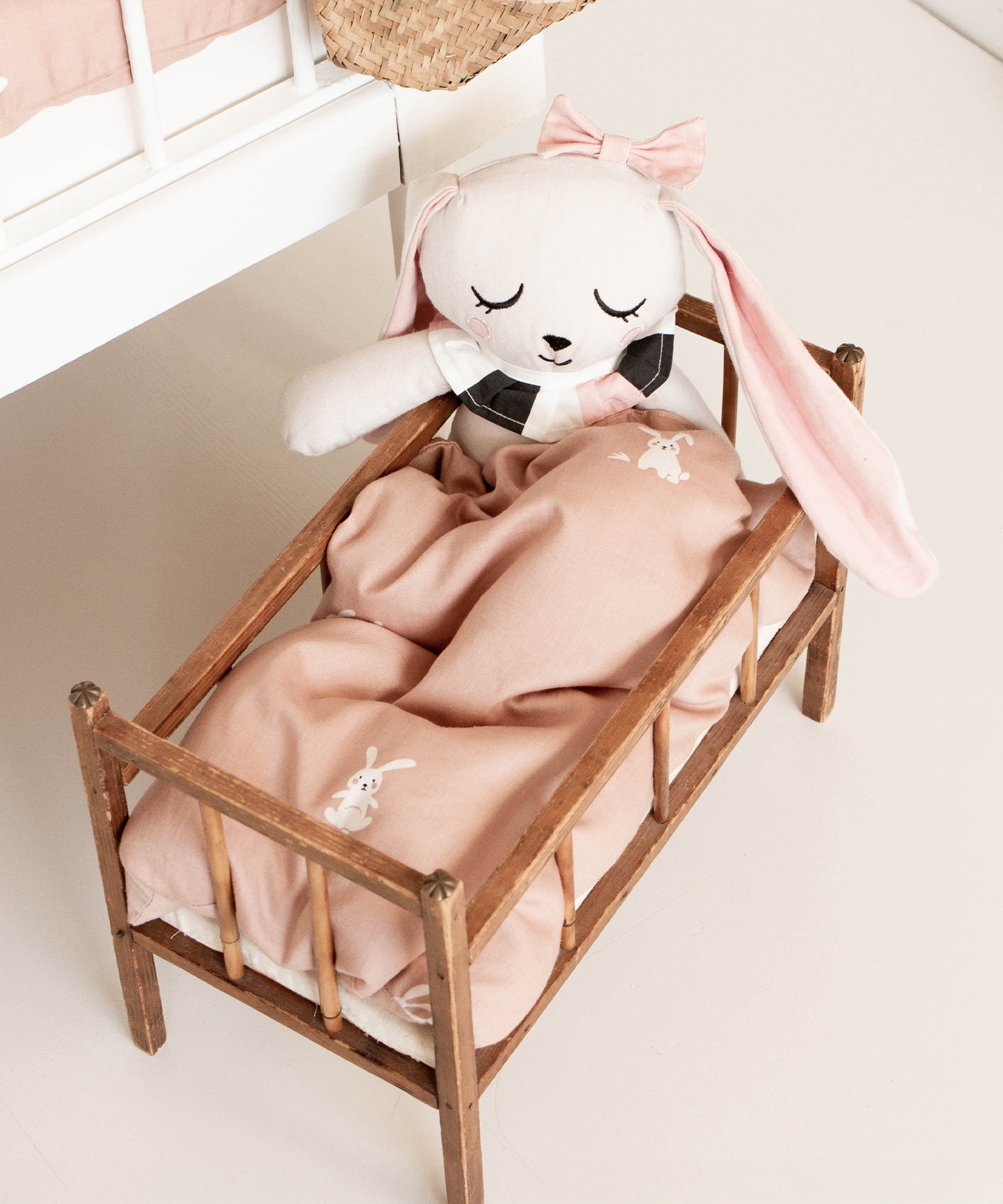 A closer look a the Roommate Doll Bedding Set - Rabbit, inside a dolls bed, with a Roommate Rabbit teddy