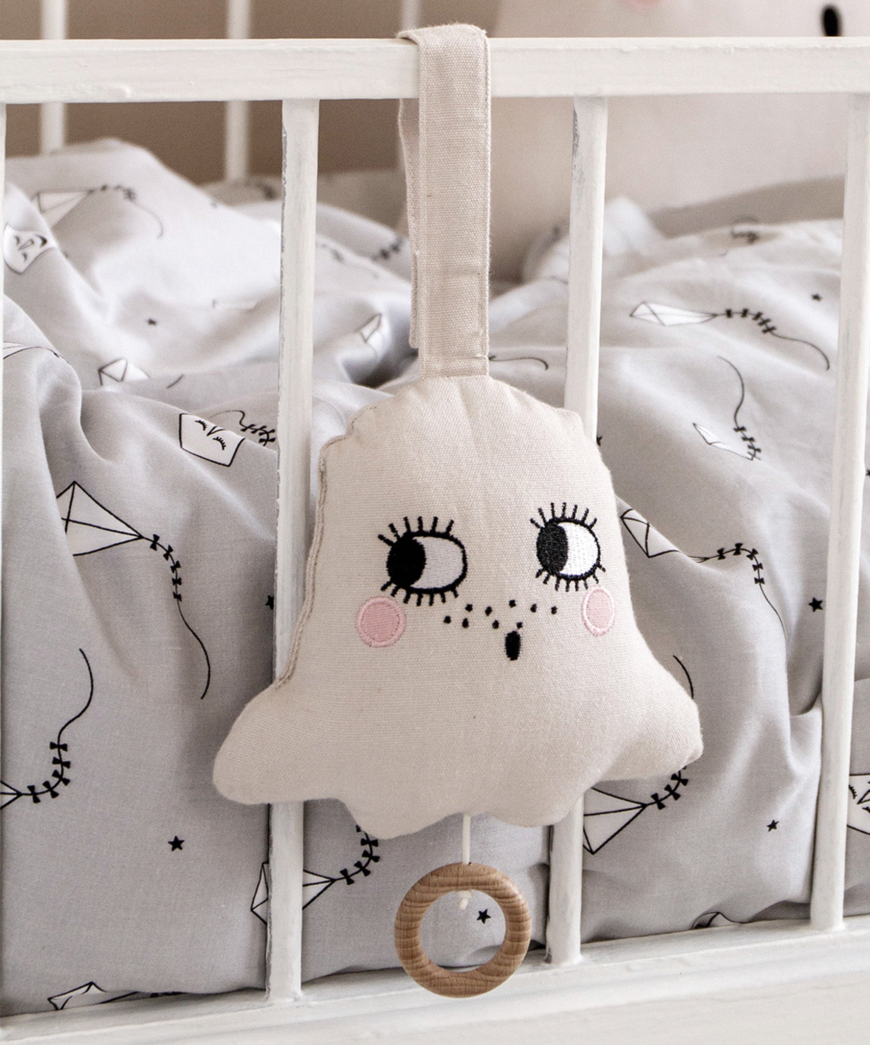 A closer view of the Roommate Ghost Lullaby Musical Mobile - Off White on the side of a crib