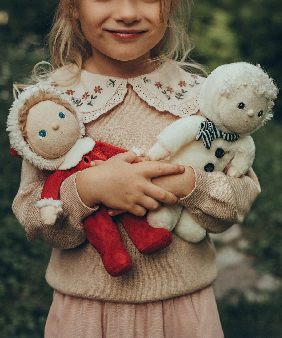 A child is holding the Sammy Santa and Sidney Snowman Dinky Dinkum Dolls in their arms