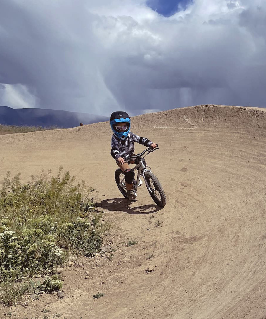 A child on a bike track, riding the Early Rider Seeker X16 16" Bike - Brushed Aluminium