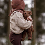 A child holding the Senger Small Floppy Brown Bear in their arms