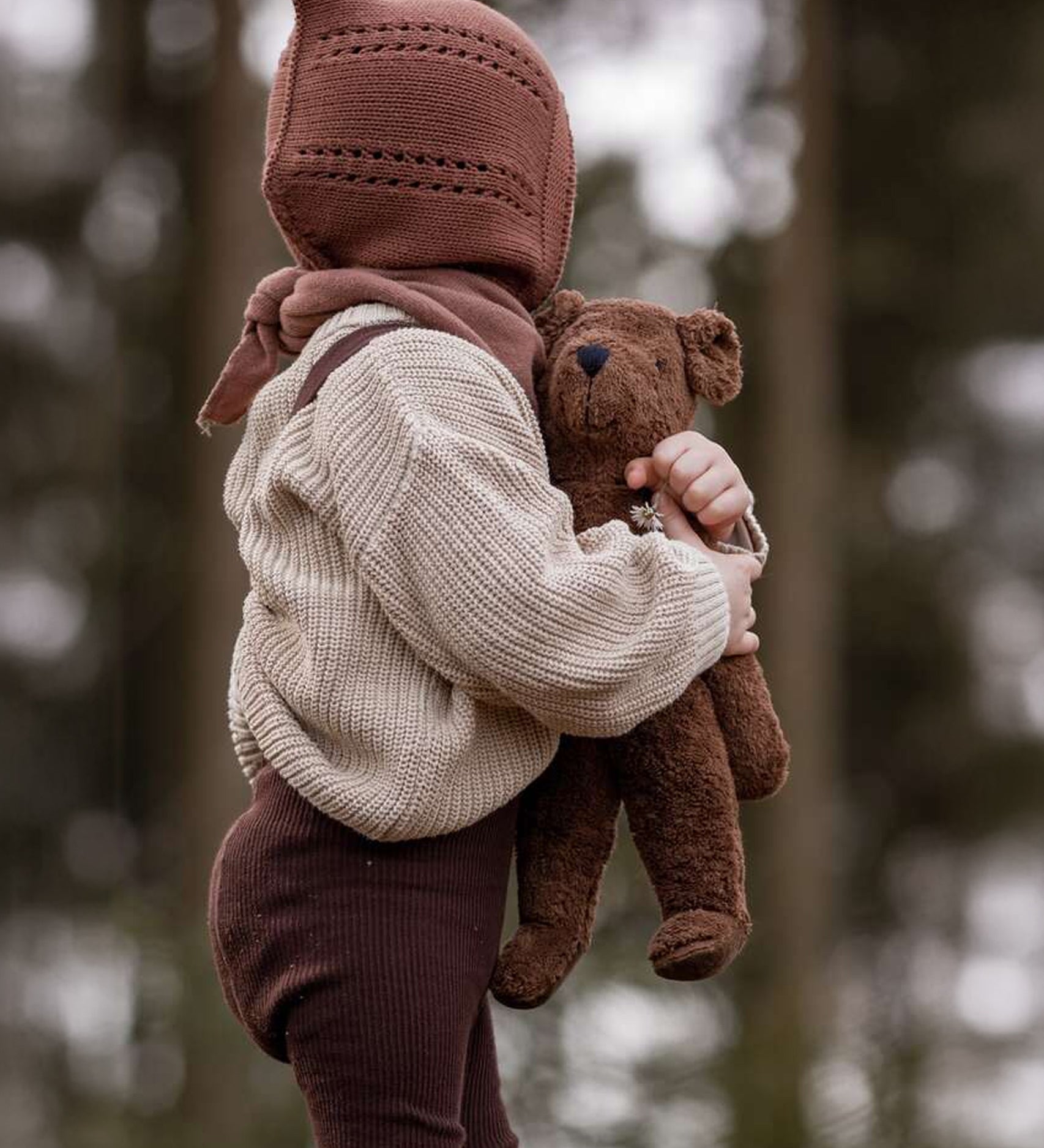 A child holding the Senger Small Floppy Brown Bear in their arms