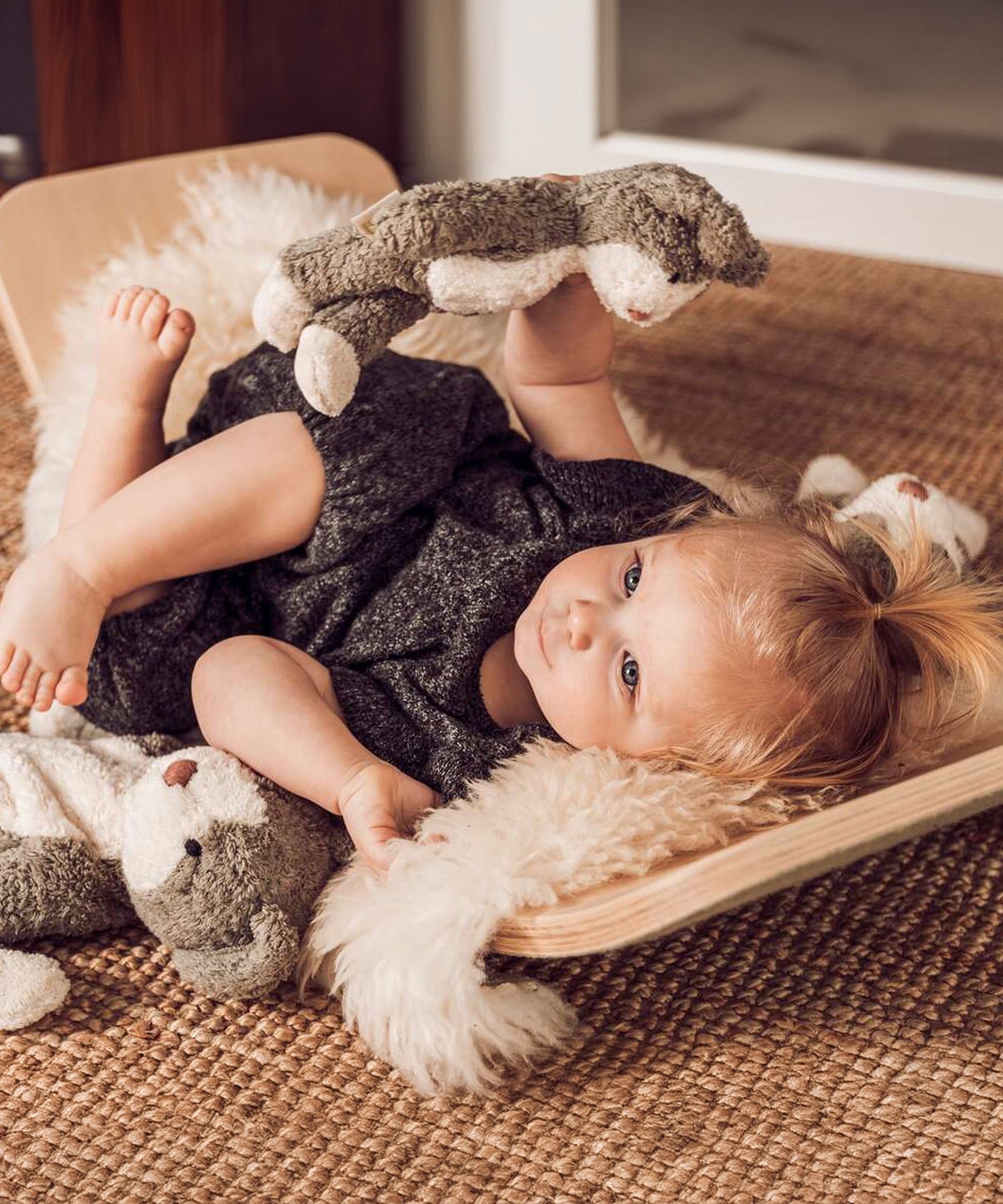 A child laying down in a Wobbel board, playing with a Senger Baby Cat