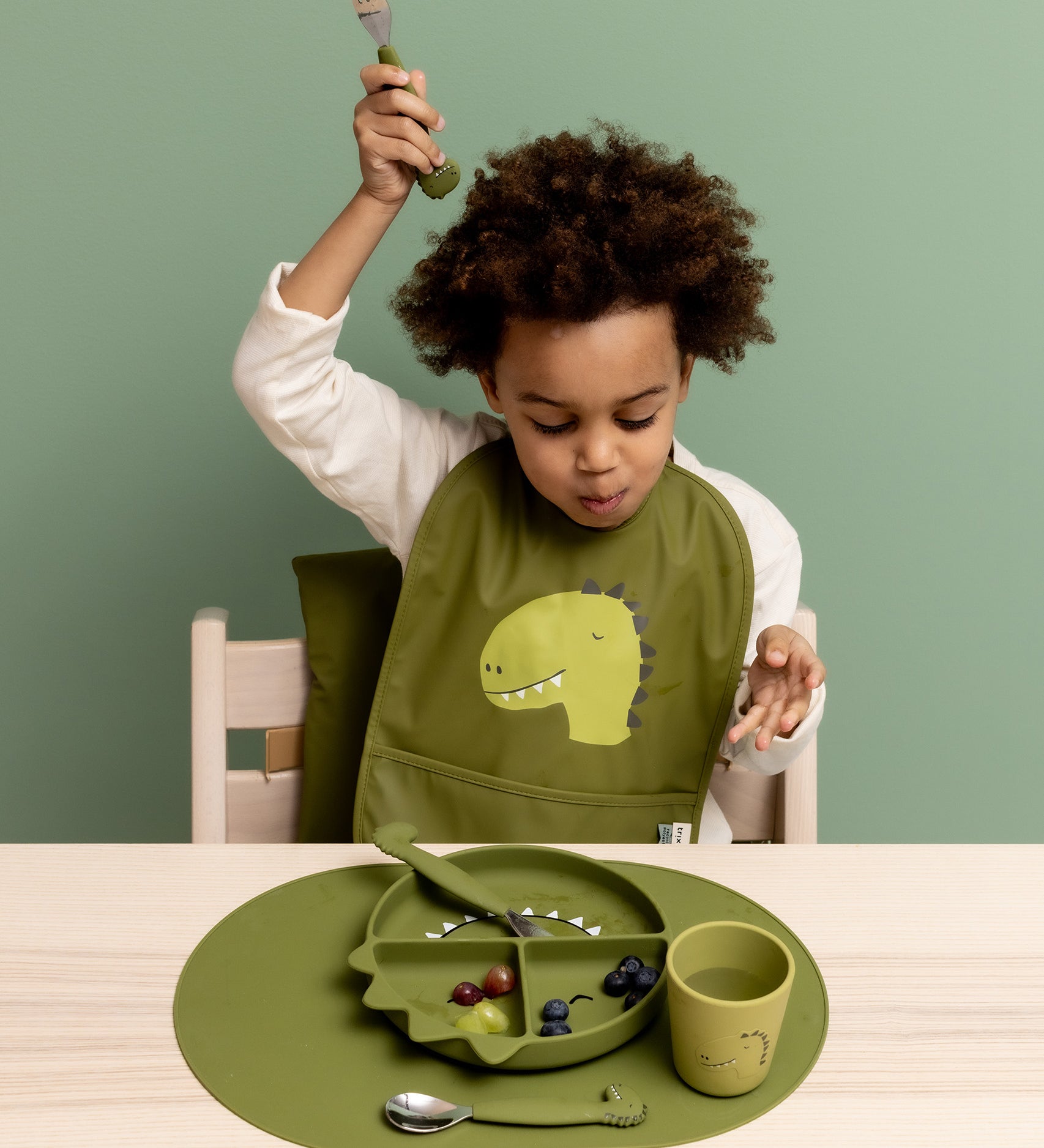 Child eating from the Trixie Animal Friends Silicone Divider Plate, green, Mr Dino. With matching bib and cutlery set. 