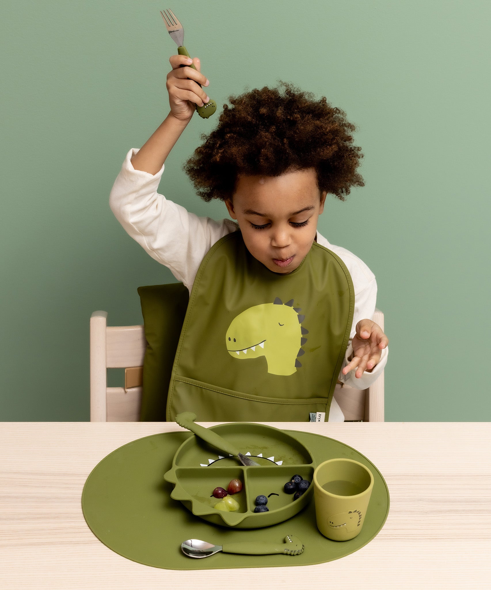 Child eating from the Trixie Animal Friends Silicone Divider Plate, green, Mr Dino. With matching bib and cutlery set. 