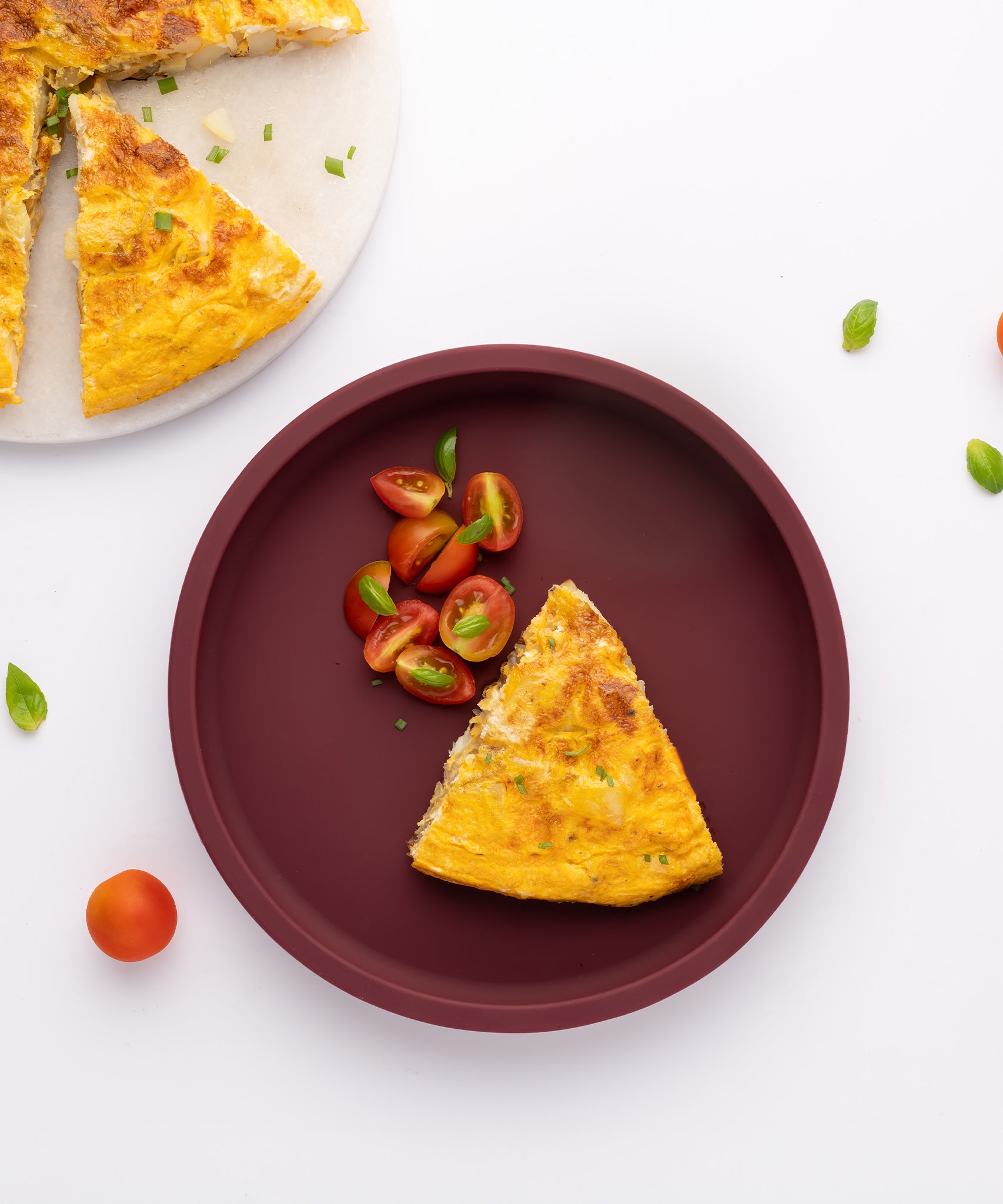 Eco Rascals Silicone Baby Plate in burgundy without divider, with a slice of quiche and tomatoes.  