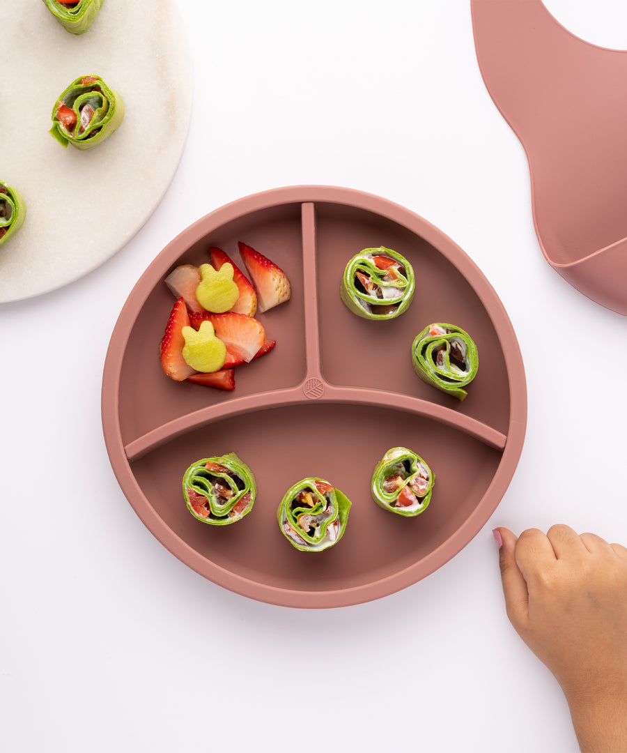 Eco Rascals Silicone Baby Plate in rose pink with removable divider, fresh fruit and green wraps.  