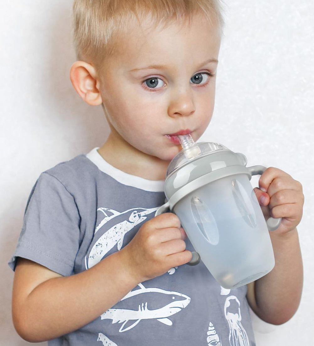 A child using the Haakaa Generation 3 Silicone Bottle Handle with the Haakaa Sippy attachment and bottle