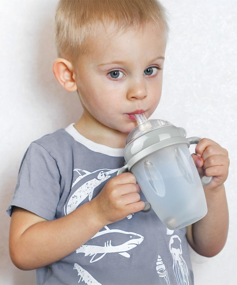 A child using the Haakaa Generation 3 Silicone Bottle Handle with the Haakaa Sippy attachment and bottle