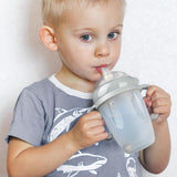 A child using the Haakaa Generation 3 Silicone Bottle Handle with the Haakaa Sippy attachment and bottle