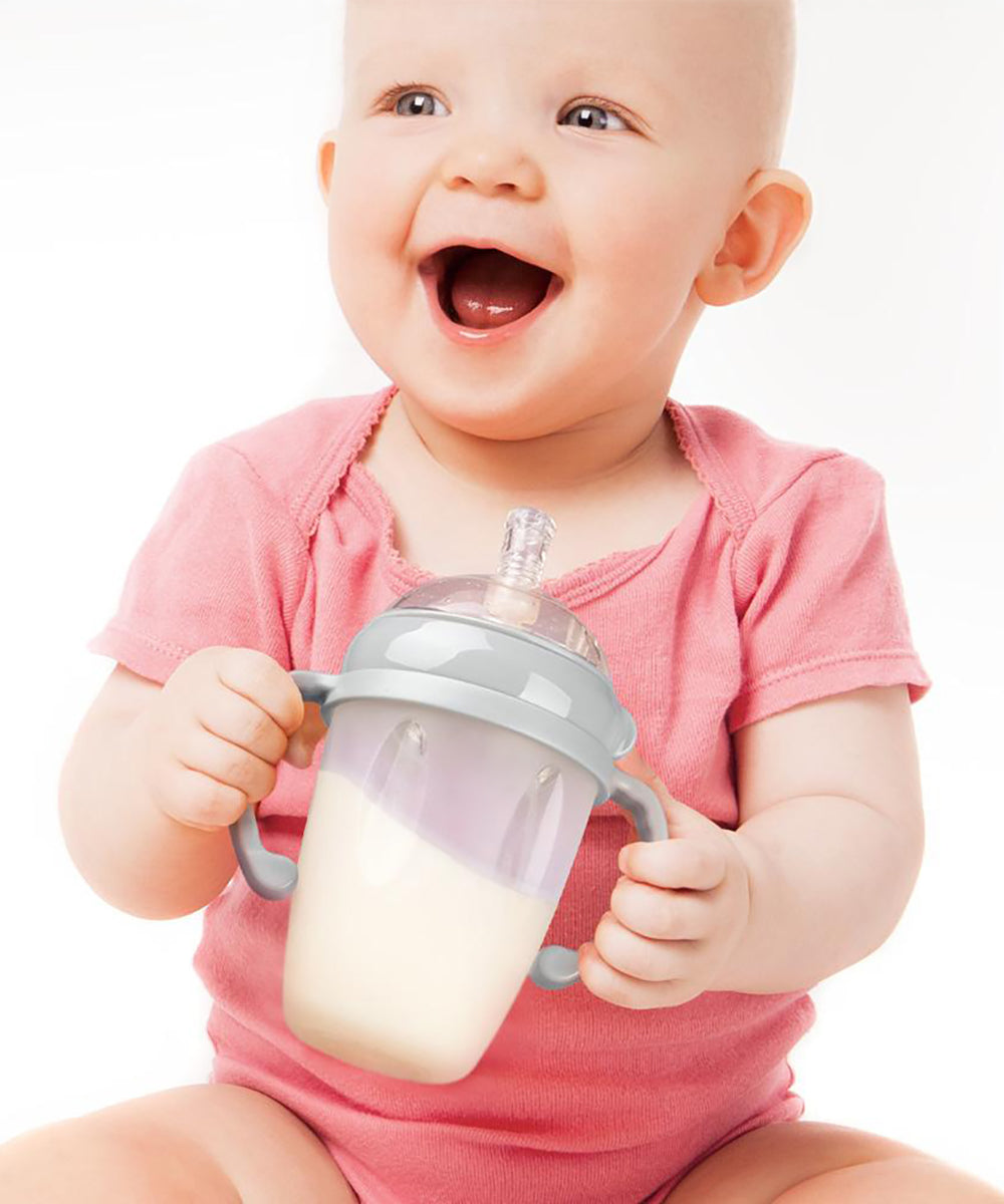 A baby smiling, and holding the Generation 3 Silicone Bottle Handle in their hands