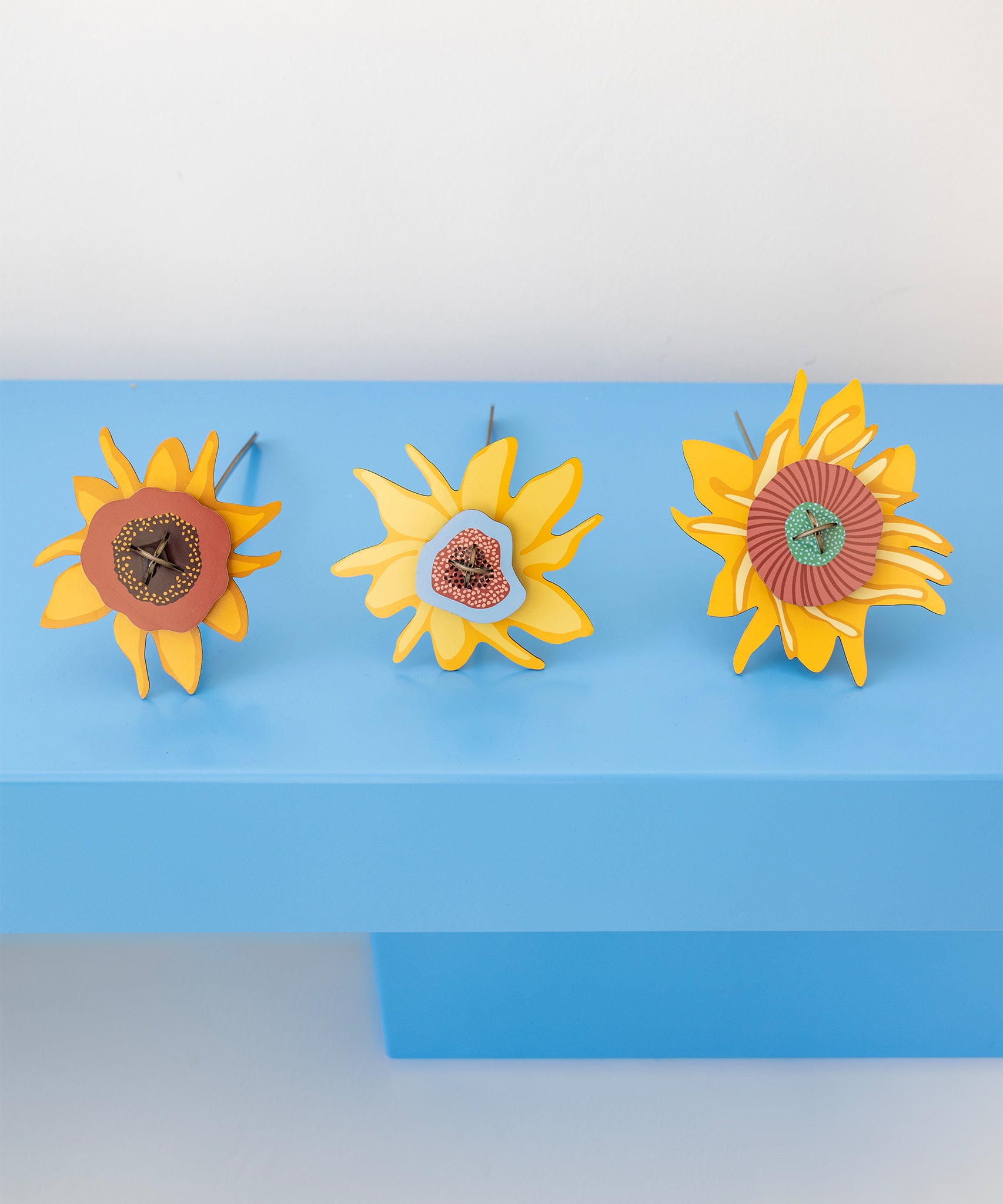 The Studio Roof Cardboard Bouquet - Van Gogh Sunflowers laid down on a blue table with the flower heads being the main focus point of the picture