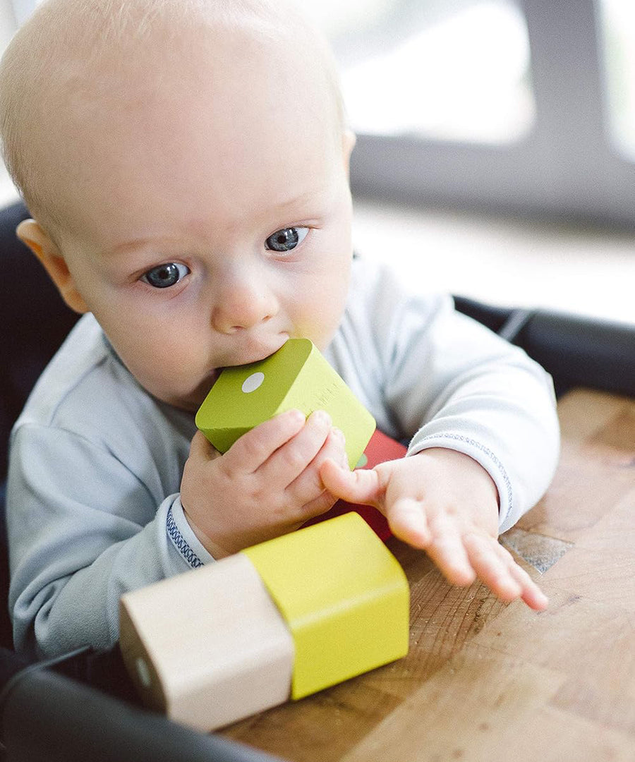 A baby teething on a block from the Tegu Baby's First Magnetic Blocks - 15 Piece