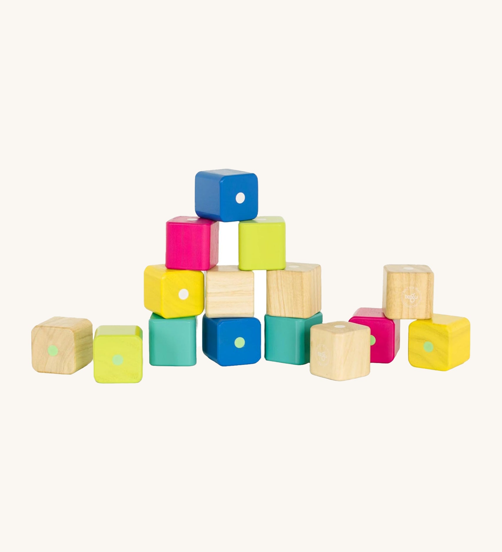 Tegu Baby's First Magnetic Blocks - 15 Piece, in natureal, yellow, pink, green and blue blocks, with some blocks stacked on top of each other on a cream background