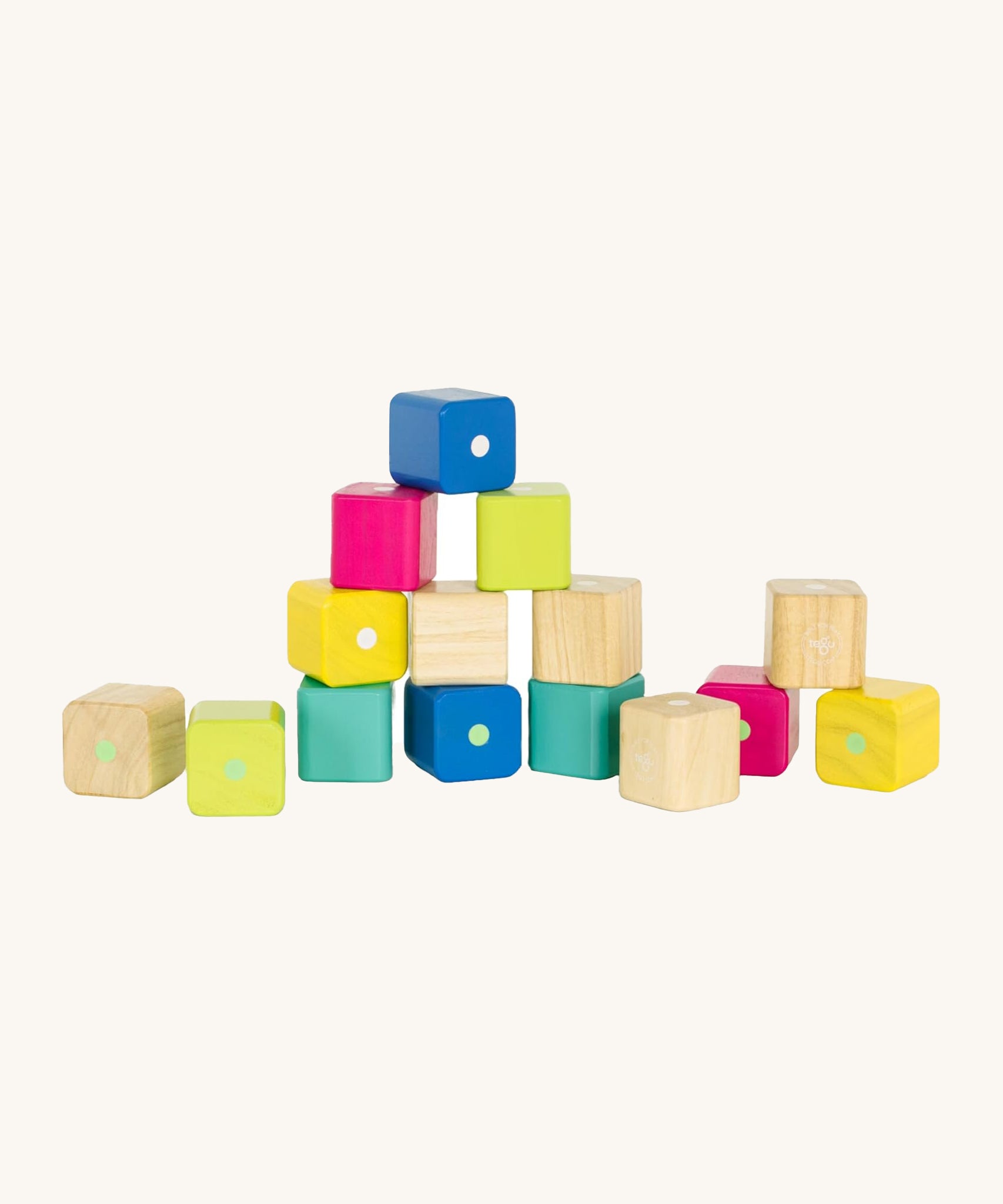 Tegu Baby's First Magnetic Blocks - 15 Piece, in natureal, yellow, pink, green and blue blocks, with some blocks stacked on top of each other on a cream background