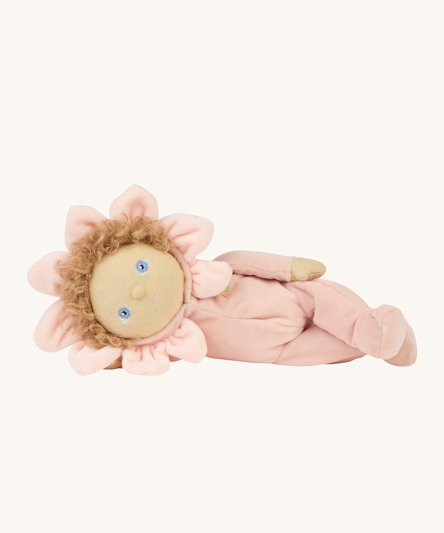 A light pink dinky dinkum doll lying down on a cream background.