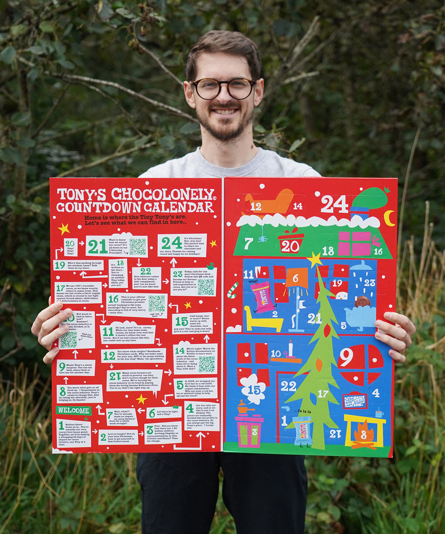 A person holding the Tony's Chocolonely Advent Calendar showing the inside which has one side filled with chocolates and the other side which has fun facts and ideas to do for the day