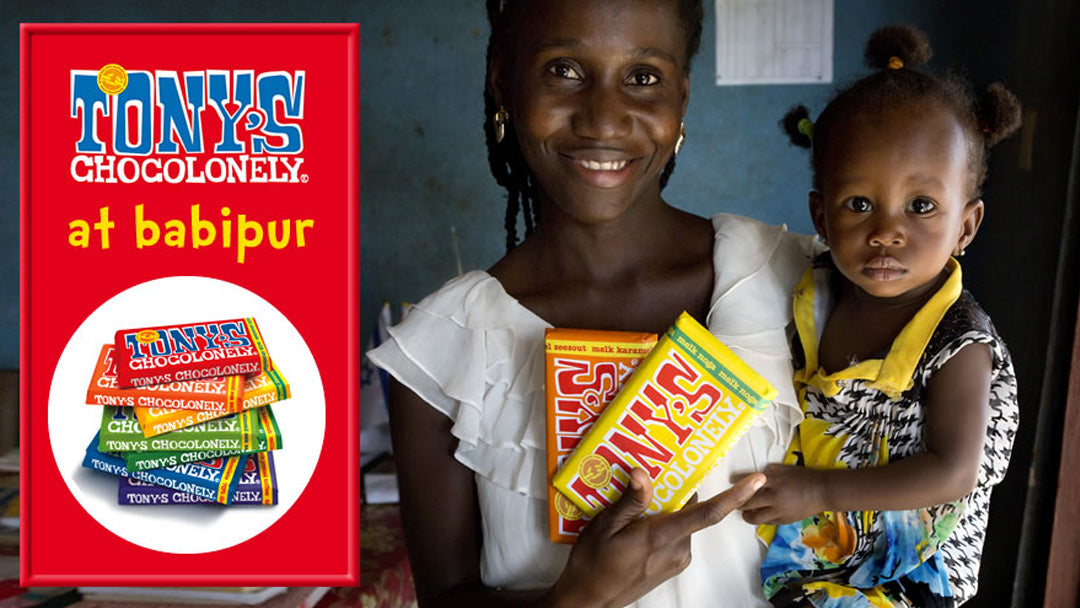 Picture of one of the farmers who farm the cocoa for Tony's Chocolonely, carrying a Tony's bar and her baby