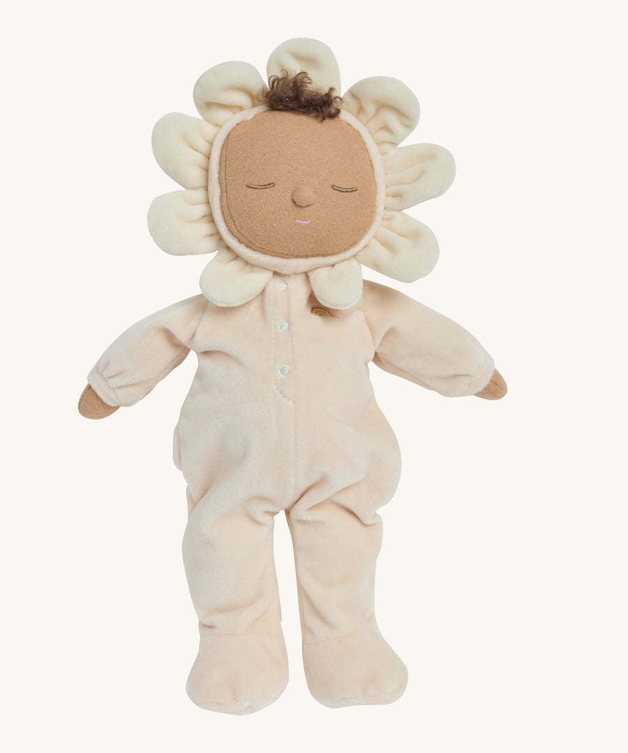 A light cream dozy dinkum doll standing up on a cream background.