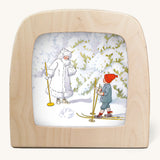 An illustration of a child skiing and meeting Jack Frost in a snowy wooded area from Ollie's Ski Trip Toverlux StoryLux Silhouette Sets, by Elsa Beskow. The illustration is inside a Magic Lamp on a cream background